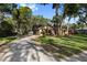 Exterior view showcasing a long, paved driveway leading to a cozy single-story home with a lush green lawn at 2932 Chelsea Woods Dr, Valrico, FL 33596