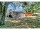 The backyard showcases the exterior of the house, enveloped by the shade of a mature tree at 3003 E 27Th Ave, Tampa, FL 33605