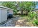 View of the backyard and the side of the house, revealing the air conditioning unit and natural landscaping at 3003 E 27Th Ave, Tampa, FL 33605