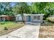 Inviting single-Gathering home featuring a well-maintained lawn, a concrete driveway, and a blue front door at 3003 E 27Th Ave, Tampa, FL 33605