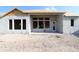 The new home shows concrete block construction with large window openings and a sliding glass door, set in a sandy lot at 31418 Hayman Loop, Wesley Chapel, FL 33545
