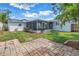 Backyard view featuring a brick patio, lush green grass, a screened-in patio, and mature landscaping at 3709 W Santiago St, Tampa, FL 33629