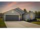 Charming single-story home features a two-car garage, manicured lawn and a colorful sunset at 4105 Waterville Ave, Wesley Chapel, FL 33543