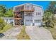 Multi-story home featuring a spacious driveway and garage with a unique exterior staircase and an upper-level balcony at 503 Chestnut St, Oldsmar, FL 34677