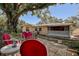 Backyard view featuring patio, outdoor seating, large tree, and charming home exterior at 5072 98Th Way, St Petersburg, FL 33708