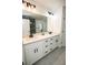 Modern bathroom with dual sinks, quartz countertops, white cabinets, and matte black hardware at 6509 Dolphin Cove Dr, Apollo Beach, FL 33572