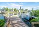 Dock view with a boat lift on the water, surrounded by lush greenery and neighborhood homes at 6509 Dolphin Cove Dr, Apollo Beach, FL 33572