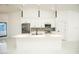 Modern kitchen with stainless steel appliances, white cabinets, large island, and mosaic tile backsplash at 6509 Dolphin Cove Dr, Apollo Beach, FL 33572