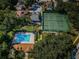 Aerial view of community pool, tennis courts and clubhouse surrounded by lush greenery at 678 Greenglen Ln, Palm Harbor, FL 34684