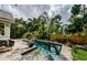 Sparkling pool with spa, surrounded by lush landscaping and a brick patio at 678 Greenglen Ln, Palm Harbor, FL 34684