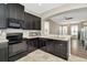 Charming kitchen boasting black cabinets, tiled flooring, and an open layout leading to the living area at 7021 White Treetop Pl, Riverview, FL 33578