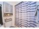 Bright bathroom showcases a shower with striped curtain and gray cabinet above the toilet at 7205 San Luis Ct, Tampa, FL 33634