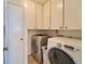 Functional laundry room with front-loading washer and dryer, ample storage cabinets, and tiled floor at 7205 San Luis Ct, Tampa, FL 33634