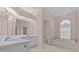 Bright bathroom with a large vanity, arched window, and tiled soaking tub at 731 Waterside Ct, Tarpon Springs, FL 34689