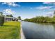 A verdant lawn extending to a waterfront view, framed by a neighboring home and lush greenery at 8727 Bay Crest Ln, Tampa, FL 33615