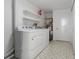 Functional laundry room with washer, dryer, shelving, patterned floors, and utility connections at 1105 Oakview Ave, Clearwater, FL 33756