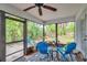 Screened-in porch featuring a ceiling fan, vibrant blue furniture, and views of the landscaped backyard at 1139 3Rd Nw Ave, Largo, FL 33770