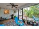 Screened-in porch featuring a ceiling fan, vibrant blue furniture, and views of the landscaped backyard at 1139 3Rd Nw Ave, Largo, FL 33770