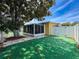Backyard featuring artificial turf, mature landscaping, and a screened lanai at 11634 Meadow Dr, Port Richey, FL 34668