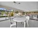 Enclosed patio featuring white tables and chairs with view of pool, tennis court, and tropical landscape at 12400 Park Blvd # 111, Seminole, FL 33772