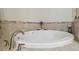 Inviting soaking tub with tile surround, decorative trim, and chrome fixtures for relaxing baths at 12531 Midpointe Dr, Riverview, FL 33578