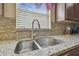 Double basin sink with granite countertops and tiled backsplash, illuminated by a bright window at 12531 Midpointe Dr, Riverview, FL 33578