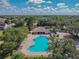 Aerial view of a community pool with a sun deck, building, parking area, and lush landscaping at 12531 Midpointe Dr, Riverview, FL 33578