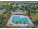 Aerial view of a large community swimming pool with palm trees and a lake nearby at 12531 Midpointe Dr, Riverview, FL 33578