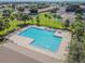Aerial view of a community pool and sundeck with lounge chairs surrounded by palm trees and greenery at 12531 Midpointe Dr, Riverview, FL 33578