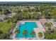 Aerial view of a community pool and sun deck with palm trees and lounge chairs in a residential area at 12531 Midpointe Dr, Riverview, FL 33578
