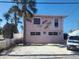 Pink two-story bungalow with palm trees and decorative lizards on the exterior wall at 12609 Sunshine Ln, Treasure Island, FL 33706