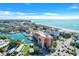 An aerial view showcasing beach, ocean, and nearby buildings and marina at 13235 Gulf Blvd # 502, Madeira Beach, FL 33708