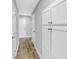Hallway featuring laminated wood flooring, storage cabinets, and white doors at 13785 Oak Forest S Blvd, Seminole, FL 33776