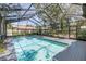 An in-ground pool is enclosed by a screen, set amidst lush greenery for ultimate privacy at 13785 Oak Forest S Blvd, Seminole, FL 33776