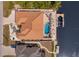 An aerial, bird's eye view showcases a waterfront home featuring a pool, patio, dock, and clay tile roof at 13878 Allamanda Cir, Port Charlotte, FL 33981