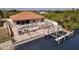 Waterfront home featuring a clay tile roof, large dock with boat lift, and stunning pool and patio area at 13878 Allamanda Cir, Port Charlotte, FL 33981