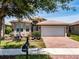Attractive home showcasing a brick driveway, manicured lawn, and vibrant landscaping at 16106 Cedar Key Dr, Wimauma, FL 33598