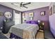 A bright bedroom featuring vibrant purple walls, a large bed, and stylish decor at 1939 Heartland Cir, Valrico, FL 33594