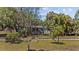 Landscaped front yard with mature trees and a charming single-story home featuring a blue trimmed roof and door at 3025 50Th St S S St, Gulfport, FL 33707