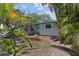 Charming single-story home showcasing a blue-trimmed door and roof, surrounded by mature trees and tropical landscaping at 3025 50Th St S S St, Gulfport, FL 33707