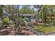 Beautifully landscaped front yard with a cozy single-story home featuring a vibrant blue door and tropical foliage at 3025 50Th St S S St, Gulfport, FL 33707
