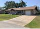 Exterior of a charming home featuring a large driveway, attached garage, and well-maintained landscaping at 31258 Park Ridge Dr, Brooksville, FL 34602
