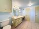 Bathroom features pale green cabinets, a long countertop, and blue walls at 38327 Palm Grove Dr, Zephyrhills, FL 33542