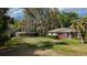 A single-story brick home with a spacious front yard and mature trees at 38327 Palm Grove Dr, Zephyrhills, FL 33542