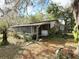 Exterior of property with screened in patio and overgrown landscaping at 38327 Palm Grove Dr, Zephyrhills, FL 33542