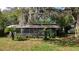 Exterior view of property with palms, and a screen enclosed porch, surrounded by a lush lawn at 38327 Palm Grove Dr, Zephyrhills, FL 33542