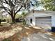 Garage and driveway with mature trees and yard at 38327 Palm Grove Dr, Zephyrhills, FL 33542