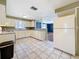 Open kitchen with view to living space; features tile floor and white appliances at 38327 Palm Grove Dr, Zephyrhills, FL 33542