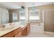 Bright bathroom featuring dual sinks, a soaking tub, and a glass-enclosed shower at 416 Durham Shore Ct, Apollo Beach, FL 33572