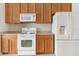 Well-lit kitchen featuring wooden cabinets, white appliances, and light countertops for a functional cooking space at 416 Durham Shore Ct, Apollo Beach, FL 33572
